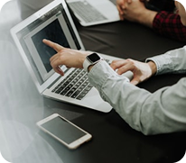 A person pointing to a laptop screen during a meeting